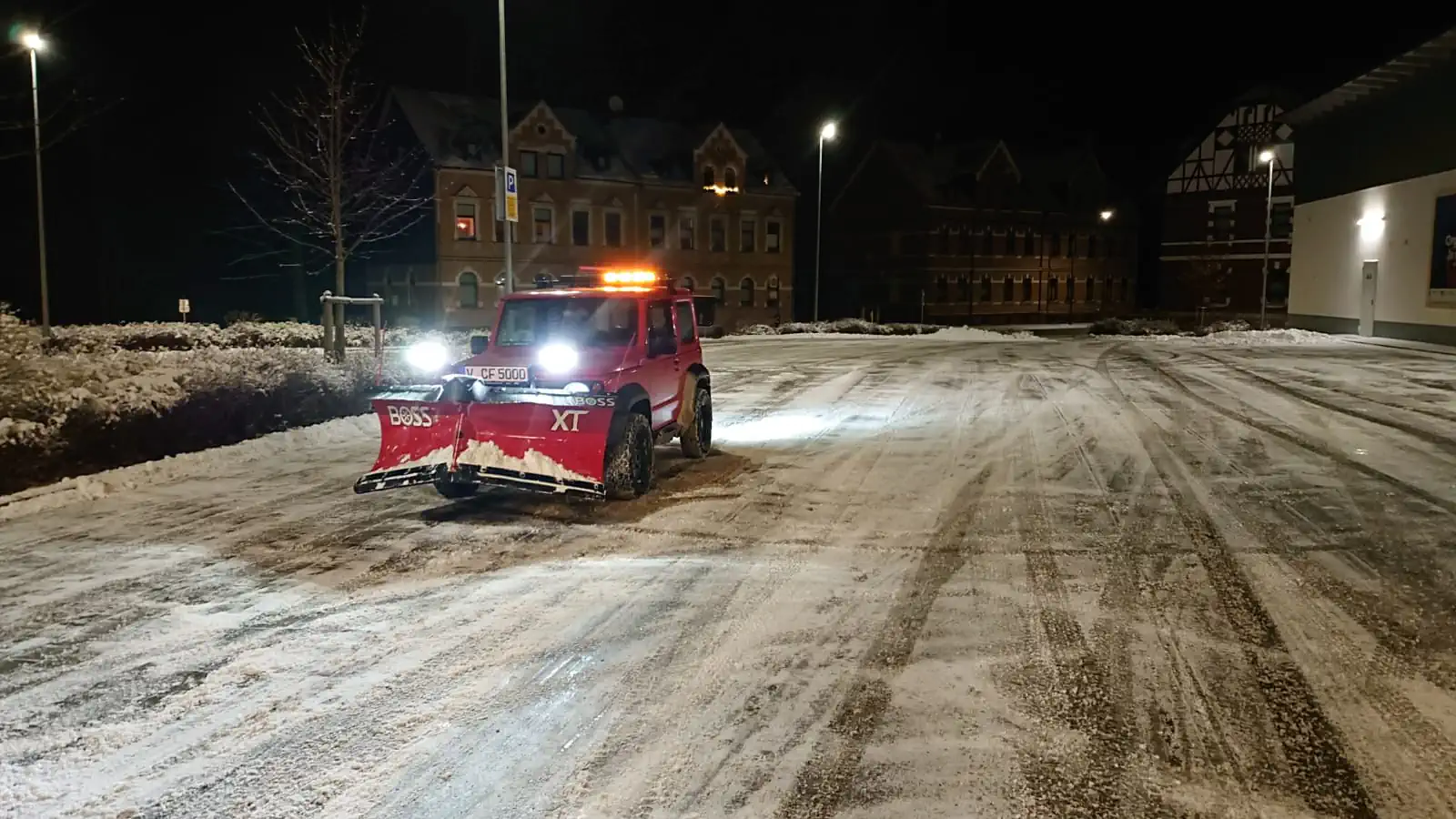 Nächtlicher Winterdienst auf einem Parkplatz mit Suzuki Jimny und Schneepflug